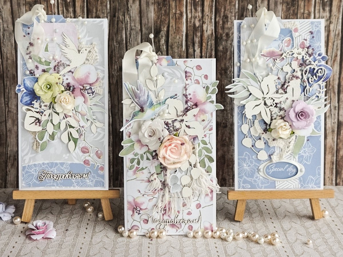 Three handmade pastel greeting cards with paper flowers on small easels